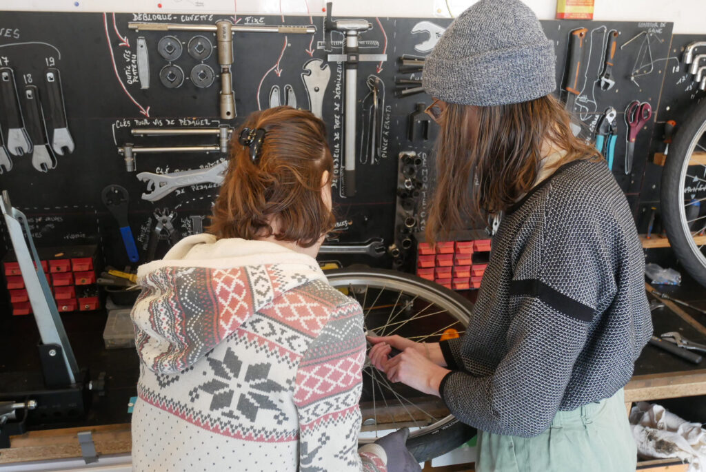 Deux bénévoles en train de réparer une roue de vélo dans l'atelier de l'association à clermont-ferrand